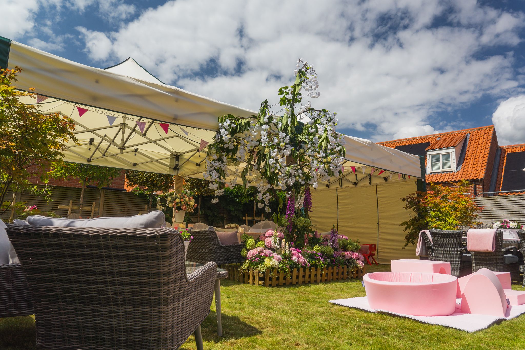 Two linked 4.5m x 4.5m mini marquee gazebos beautifully dressed with floral arrangements, bunting, and pink lounge furniture for a summer garden party in Everton, Bawtry